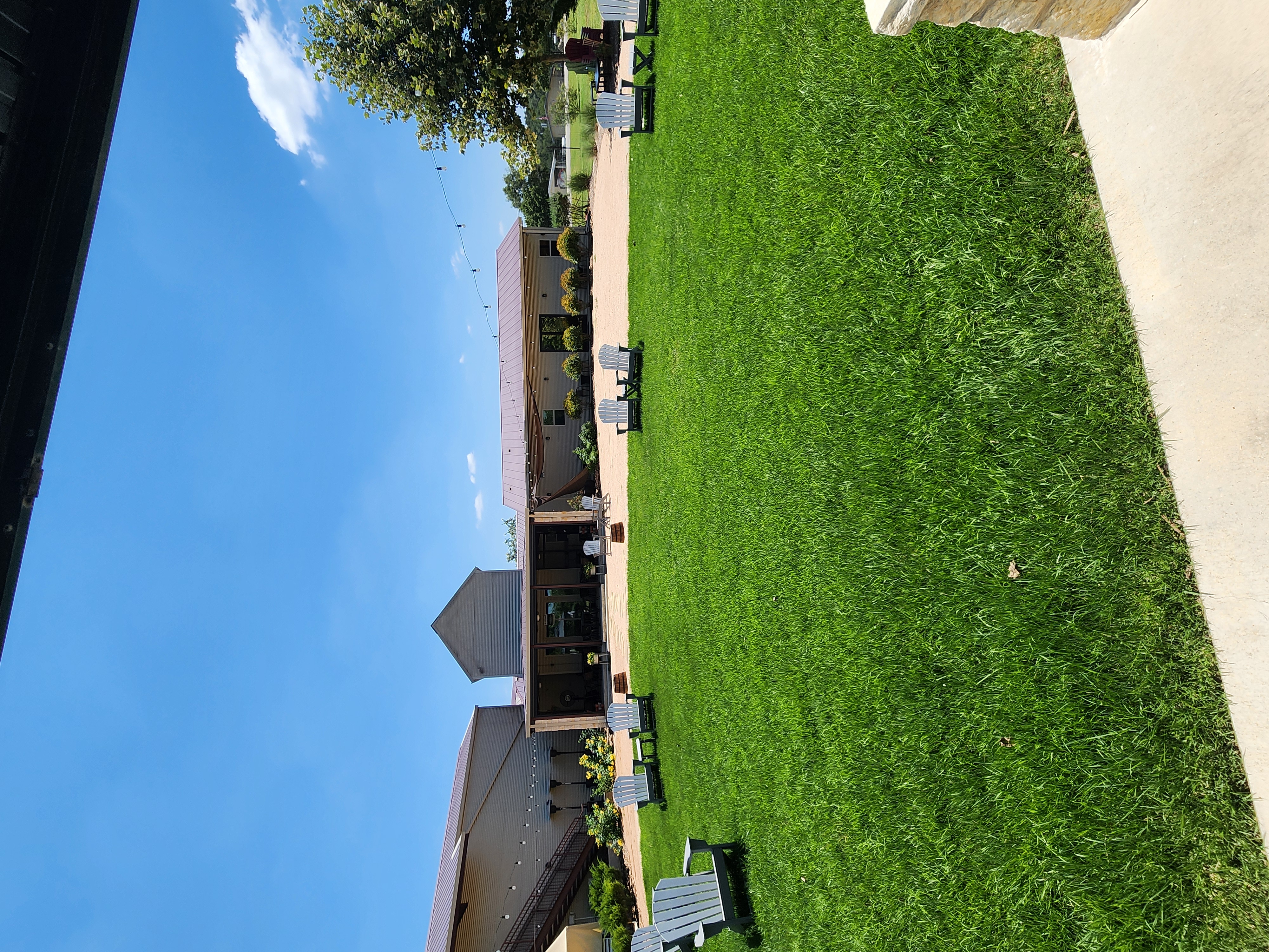 Kai-Simone Winery lush green garden lawn with Adirondack chairs, string lights and blue sky