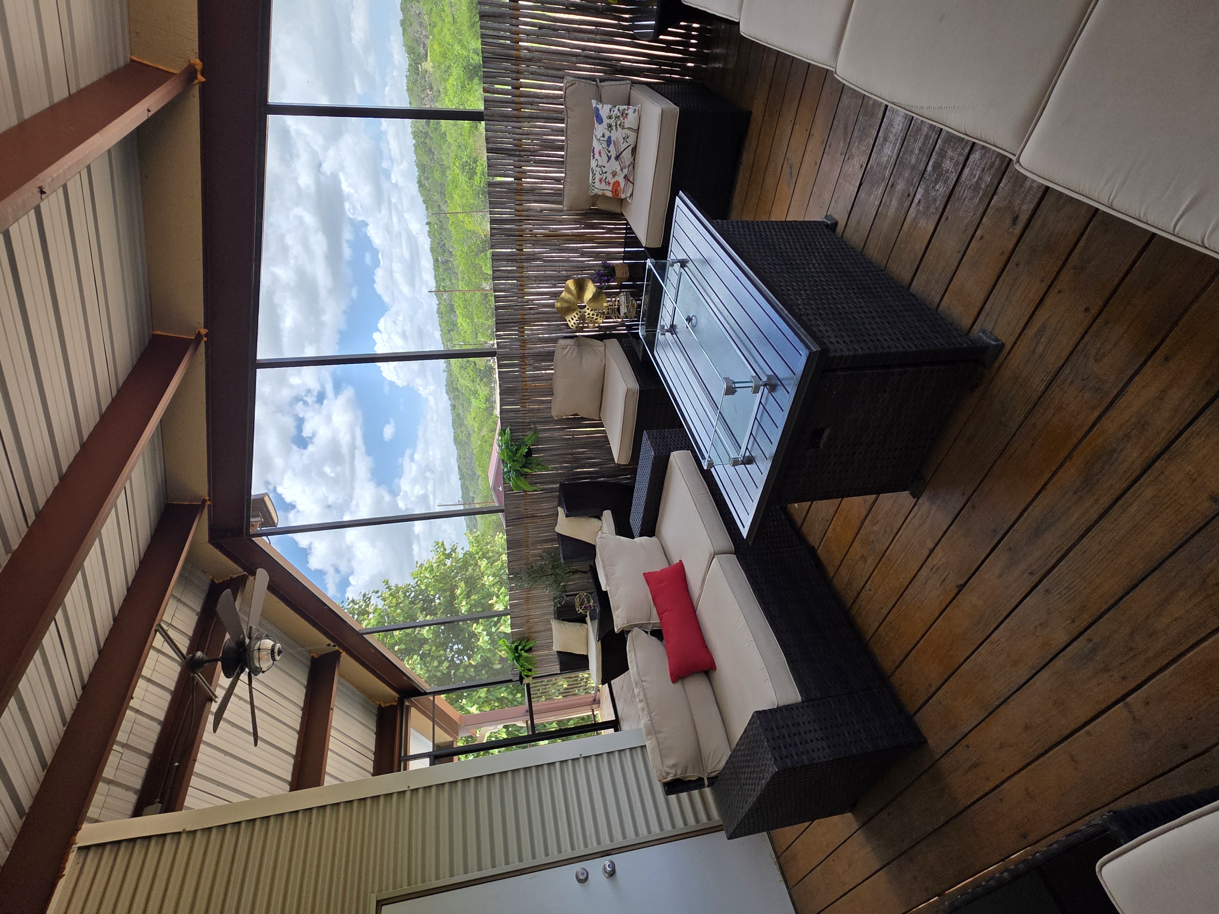 Kai-Simone Winery screened balcony lounge area with red accent pillow, glass fire table and Hill Country skyline