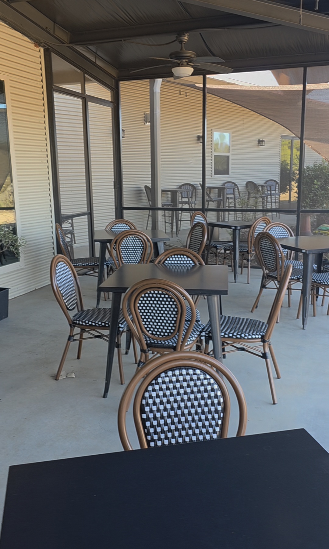 Kai-Simone Winery outdoor patio with black tables and woven bistro chairs